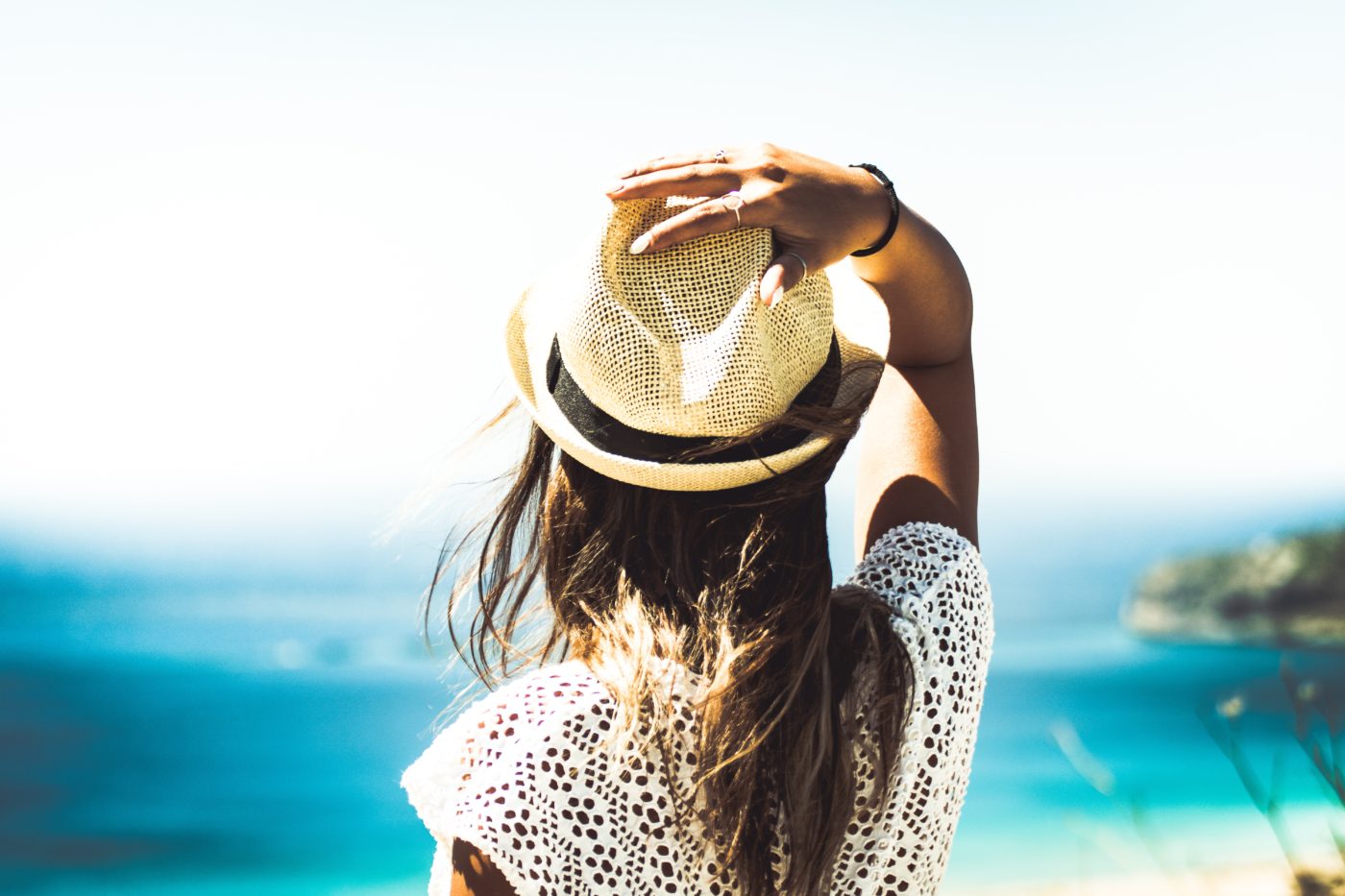 A woman with her back turned looking out at the beach