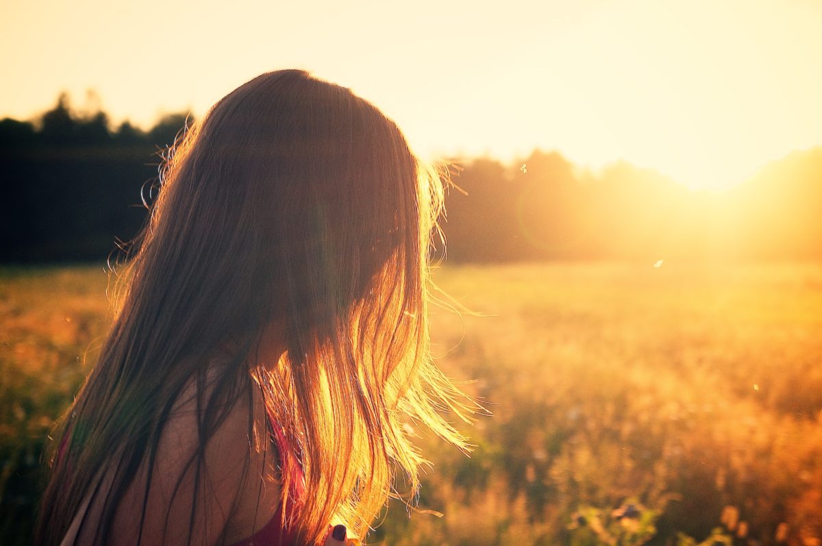 A young woman standing in a field during sunset