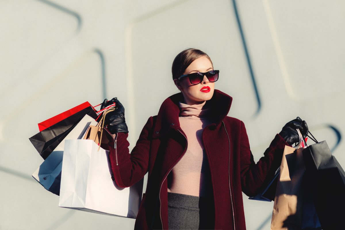 A polished, expensively dressed woman holding a ton of shopping bags