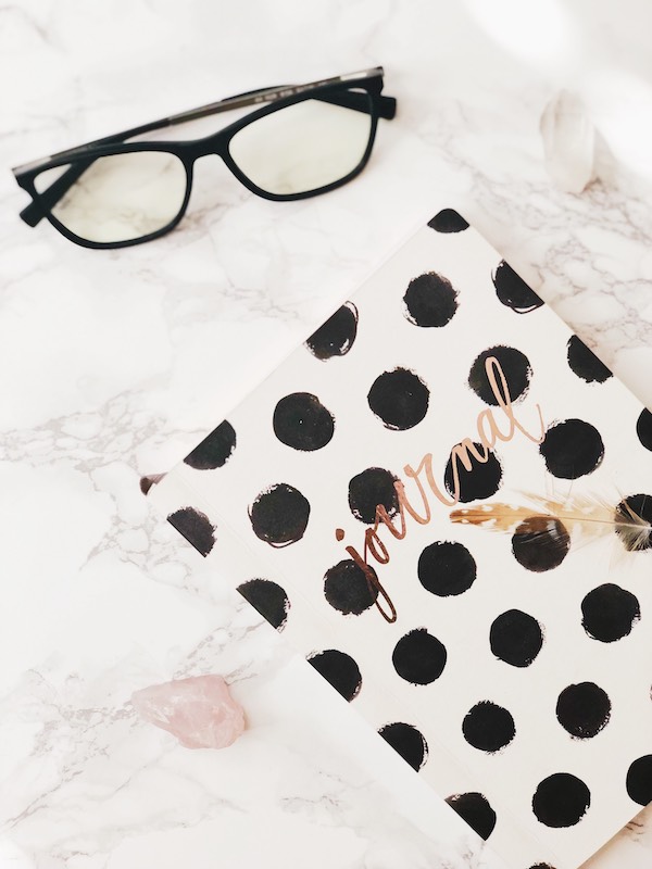 A journal, glasses, rose quartz, clear quartz